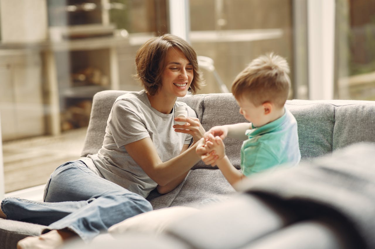 A heartwarming moment of a mother and son sharing laughter and joy on the sofa indoors.