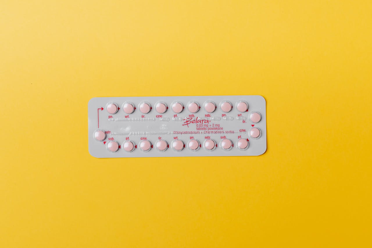 Close-up of a blister pack of pink pills on a vivid yellow background for medication concept.