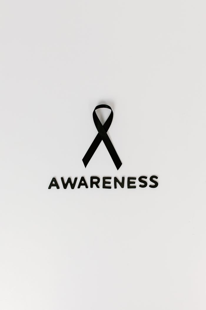 Minimalist image of a black ribbon symbolizing cancer awareness with text.